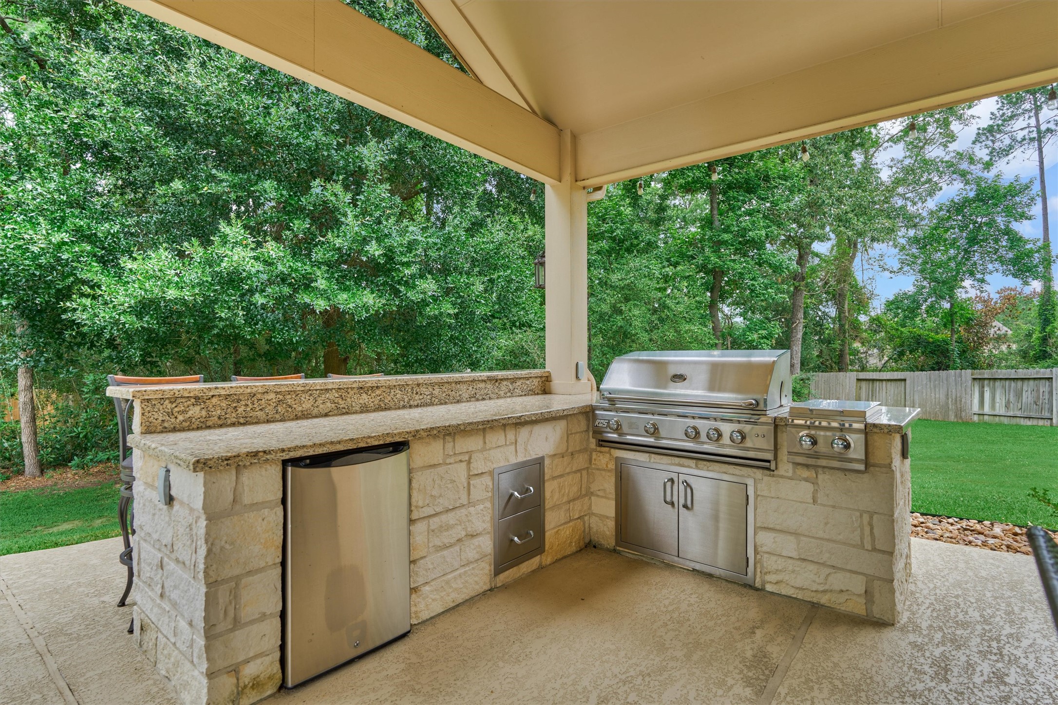 2500 Eagle Post Drive Conroe, TX 77304 - Photo 43 of 50 Shaded outdoor kitchen features grill, cooktop and beverage cooler alongside a granite prep counter with bar seating!