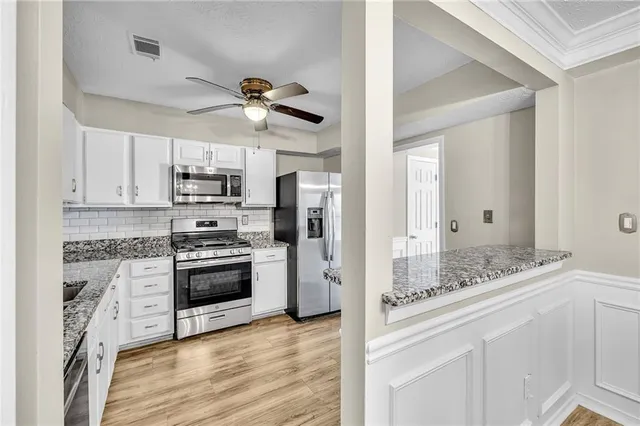 a kitchen with stainless steel appliances a stove a sink and white cabinets