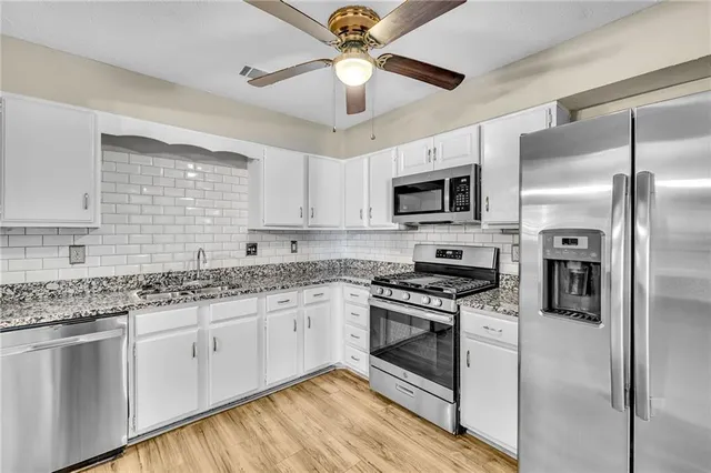 a kitchen with stainless steel appliances granite countertop a stove a sink and a refrigerator