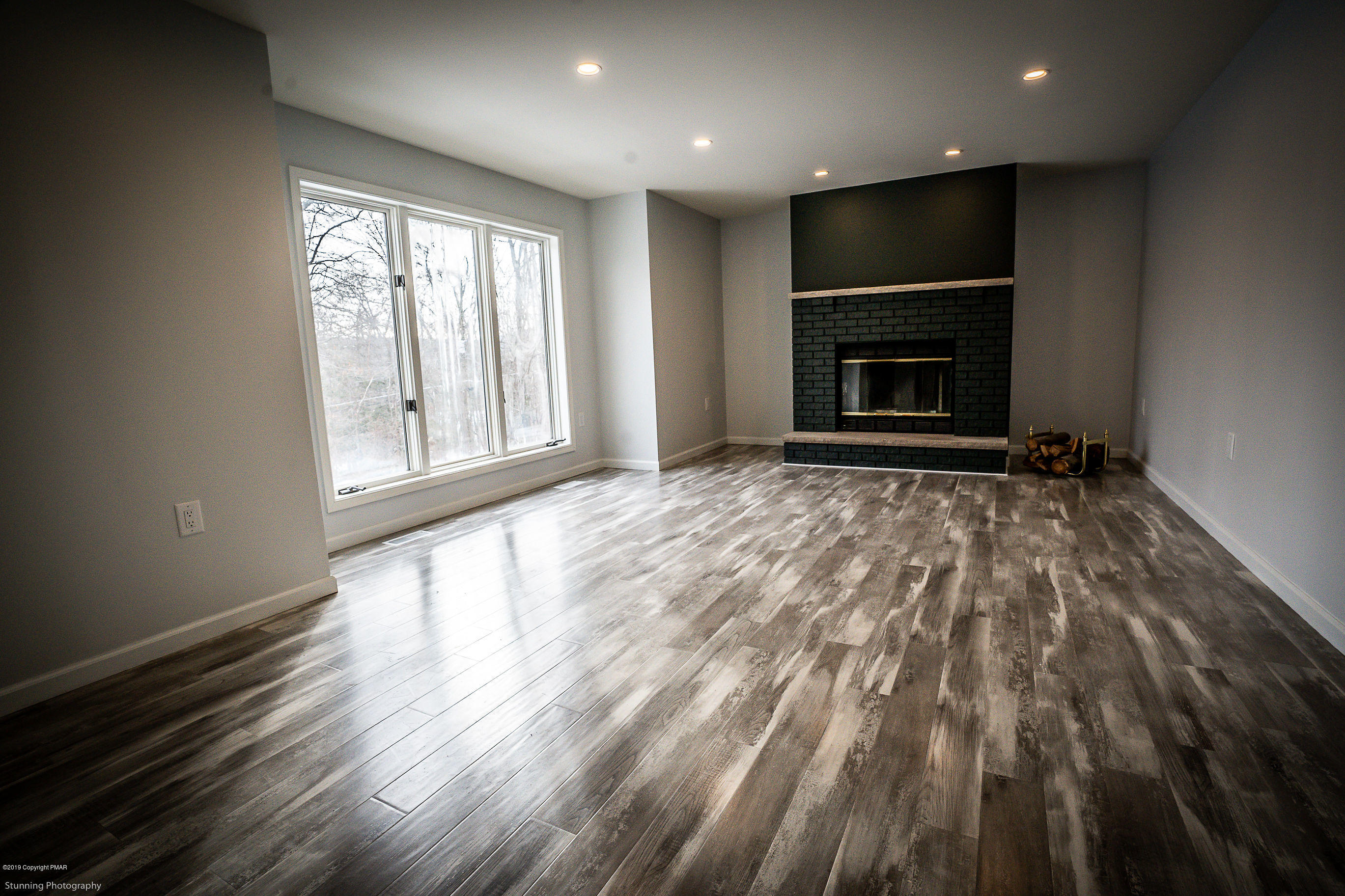 6427 Crestview Road Swiftwater, PA 18370 - Photo 8 of 16 an empty room with wooden floor fireplace and a window