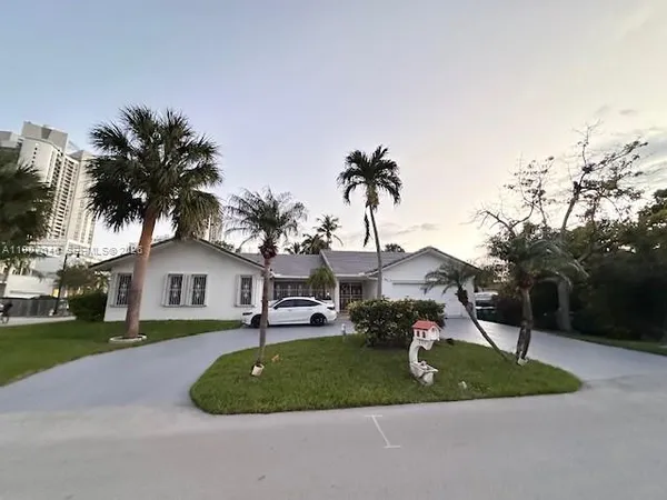 a front view of a house with a yard and palm trees