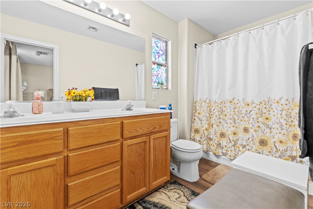 1419 Red Sunset Avenue Henderson, NV 89074 - Photo 21 of 35 Bathroom featuring double vanity, curtained shower, and dark wood-style floors