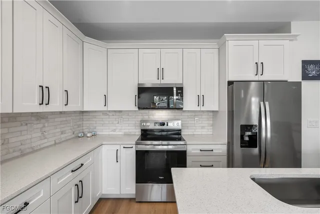 a kitchen with a sink white cabinets and stainless steel appliances