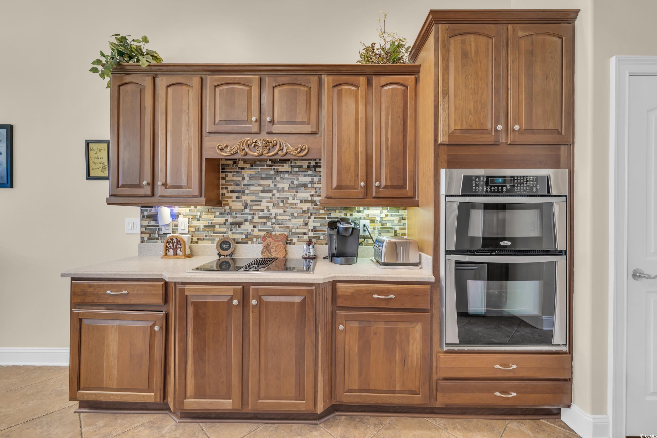 4254 Congressional Drive Myrtle Beach, SC 29579 - Photo 17 of 40 Chef's kitchen with wall oven and microwave, JennAir downdraft cooktop, ogee edge Corian countertops, tile backsplash, and soft-close cabinets.