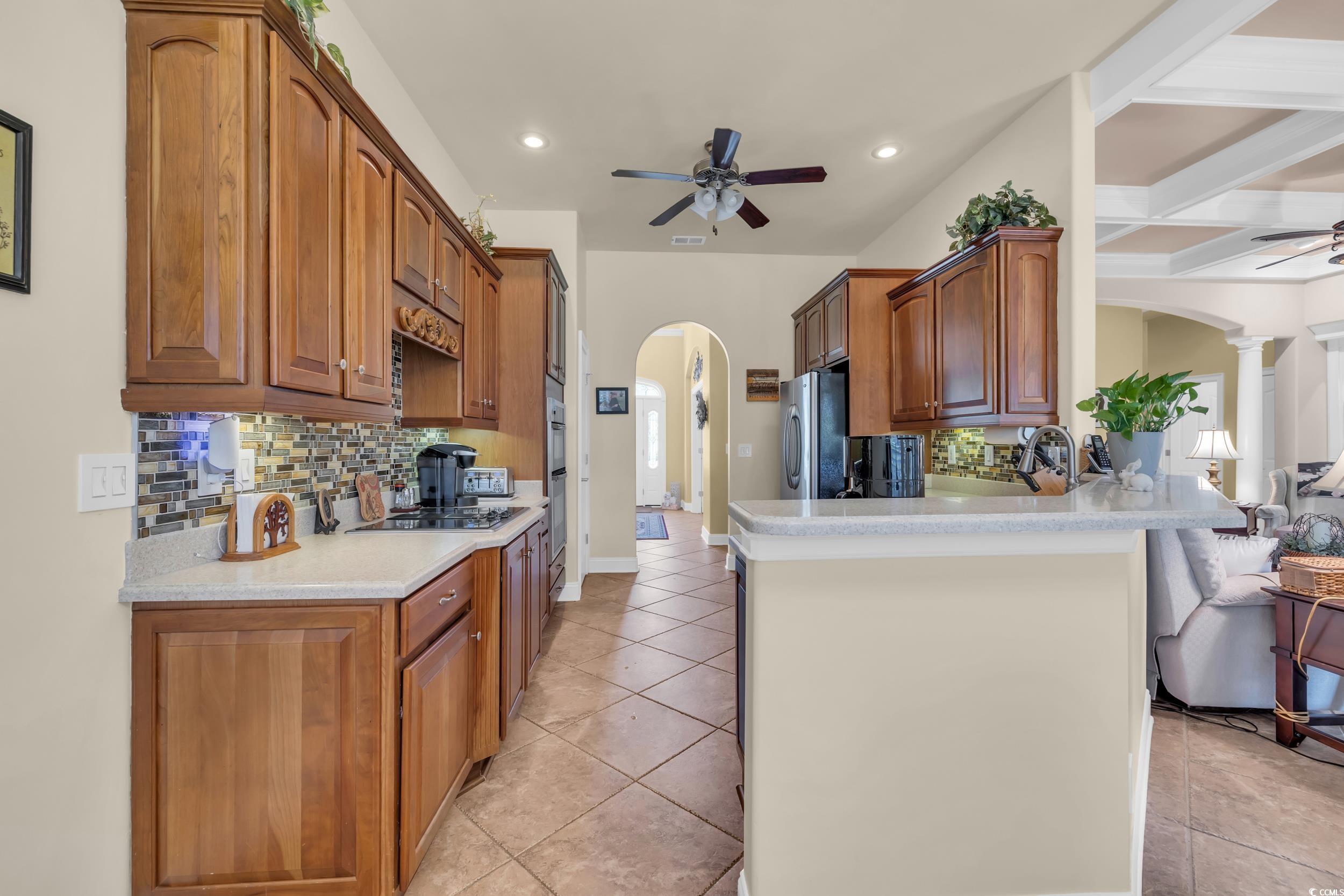 4254 Congressional Drive Myrtle Beach, SC 29579 - Photo 18 of 40 Chef's kitchen with wall oven and microwave, JennAir downdraft cooktop, ogee edge Corian countertops, tile backsplash, and soft-close cabinets.