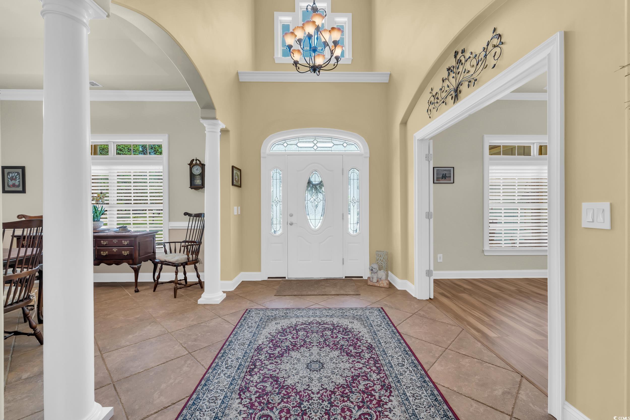4254 Congressional Drive Myrtle Beach, SC 29579 - Photo 4 of 40 Foyer entrance featuring arched doorways, ornamental molding, decorative columns, a 20' towering ceiling, and chandelier