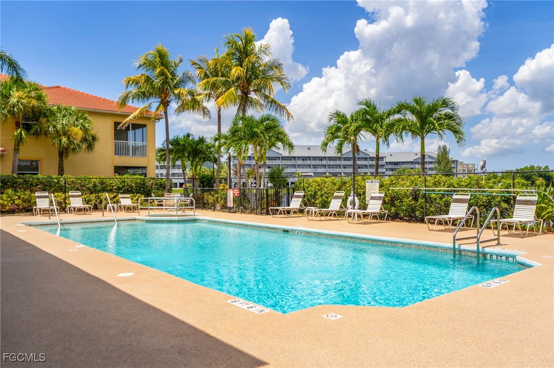 4336 Bellasol Circle, Unit 2911 Fort Myers, FL 33916 - Photo 41 of 45 a view of swimming pool with a lawn chairs under palm trees