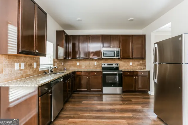 a kitchen with kitchen island granite countertop a refrigerator stove top oven and sink