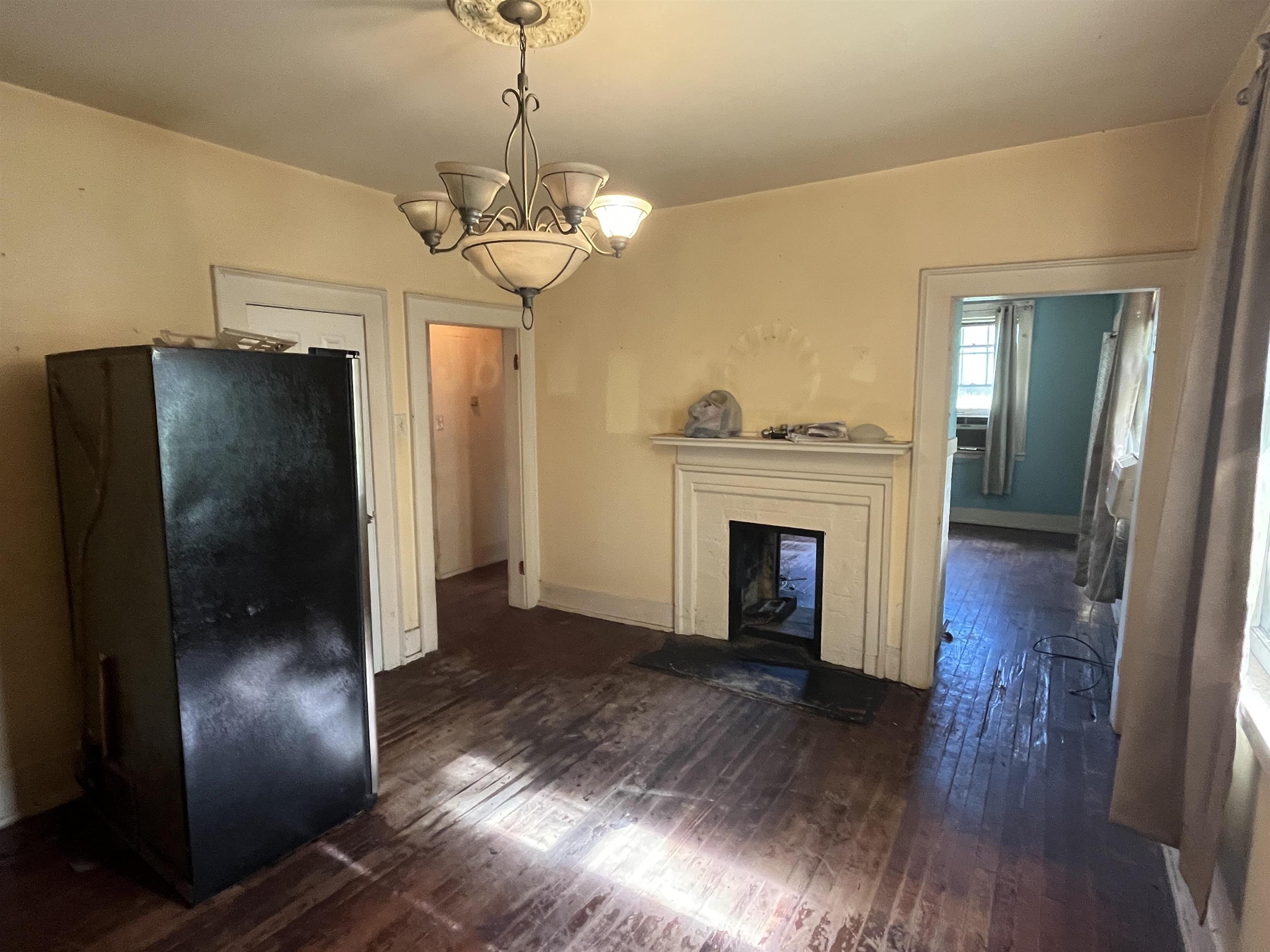 211 4th Street Mobile, AL 36611 - Photo 15 of 34 Unfurnished living room featuring dark wood-type flooring, a fireplace, and a chandelier