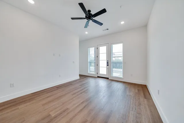 an empty room with wooden floor and windows