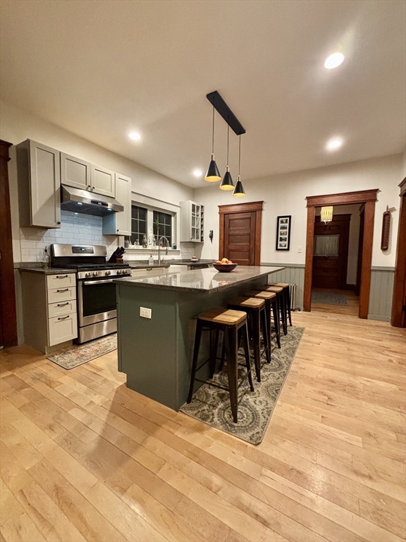 142 Sanders Avenue Lowell, MA 01851 - Photo 6 of 28 a kitchen with stainless steel appliances granite countertop a stove top oven a sink dishwasher a dining table and chairs with wooden floor