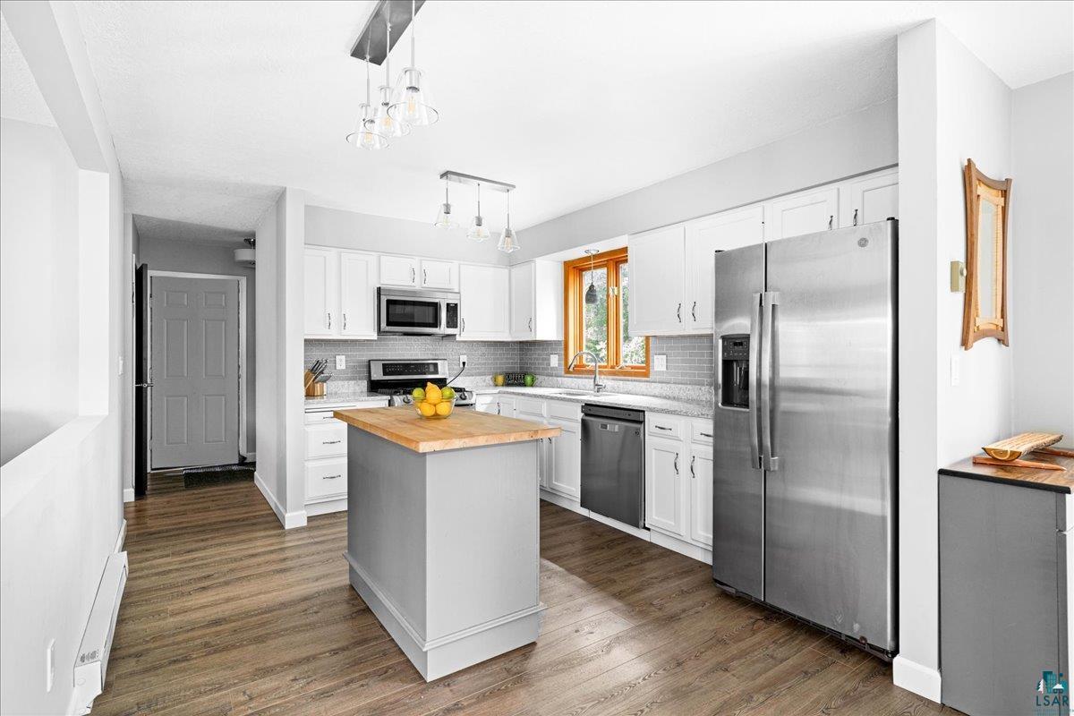 2524 Providence Road Duluth, MN 55811 - Photo 12 of 42 Kitchen featuring a center island, butcher block countertops, dark hardwood / wood-style floors, stainless steel appliances, and white cabinets