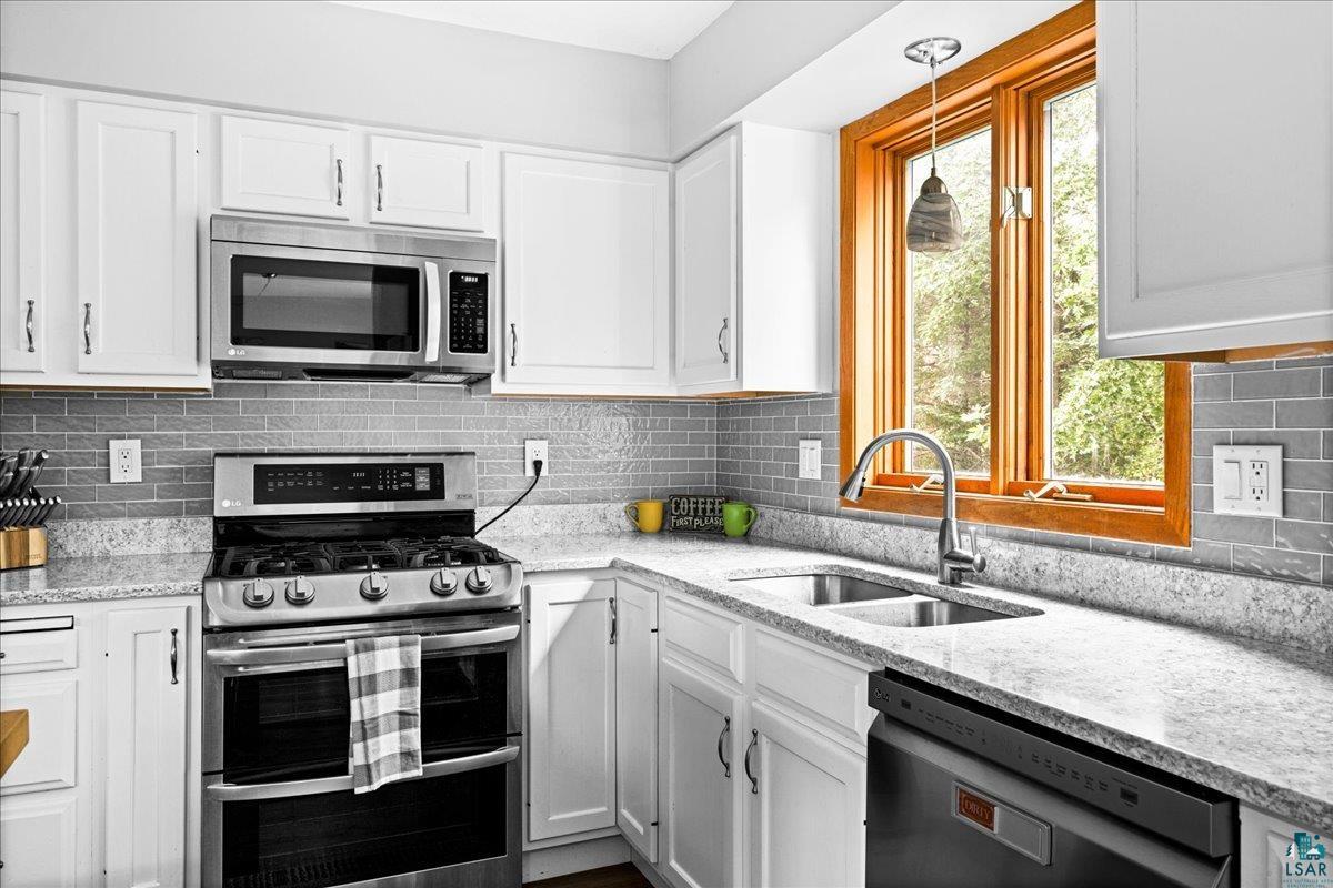 2524 Providence Road Duluth, MN 55811 - Photo 13 of 42 Kitchen with sink, decorative backsplash, light stone counters, and stainless steel appliances