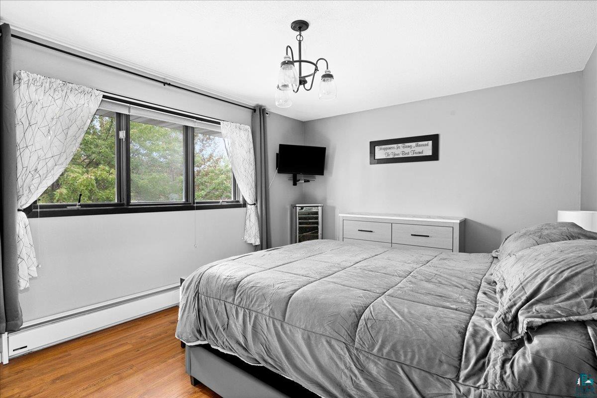 2524 Providence Road Duluth, MN 55811 - Photo 17 of 42 Bedroom featuring hardwood / wood-style flooring, beverage cooler, baseboard heating, and a chandelier
