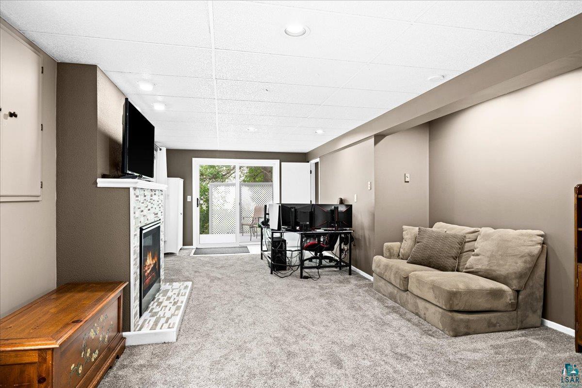 2524 Providence Road Duluth, MN 55811 - Photo 24 of 42 Living room featuring carpet floors, a drop ceiling, and a tile fireplace