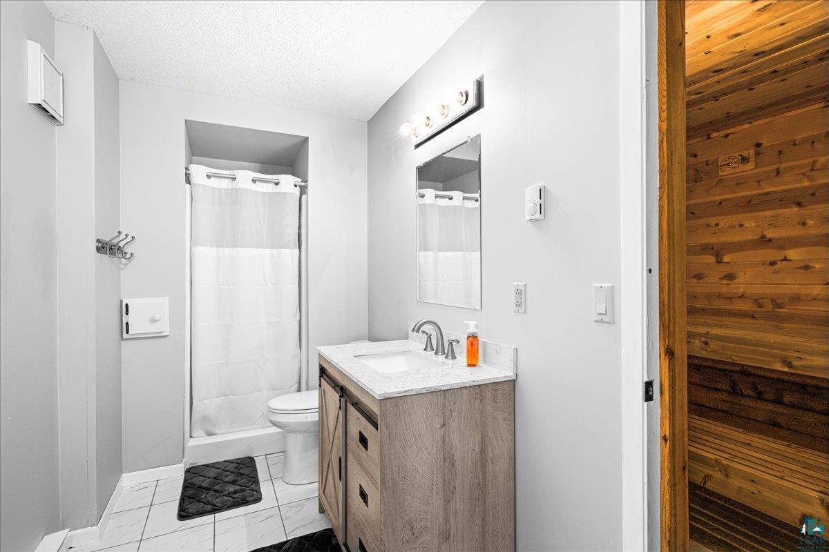 2524 Providence Road Duluth, MN 55811 - Photo 27 of 42 Bathroom with tile patterned floors, a textured ceiling, vanity, toilet, and walk in shower