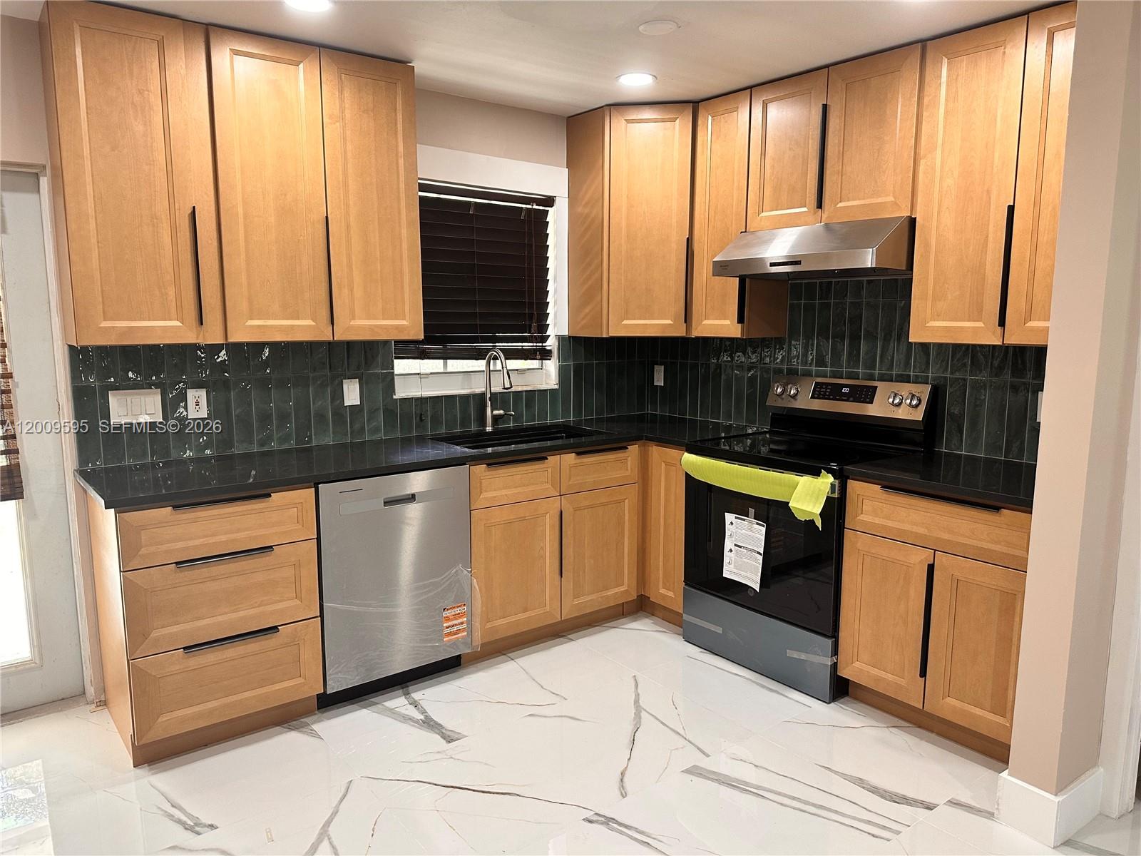 3614 Everglades Road Palm Beach Gardens, FL 33410 - Photo 2 of 9 a kitchen with stainless steel appliances granite countertop a stove a sink and a microwave