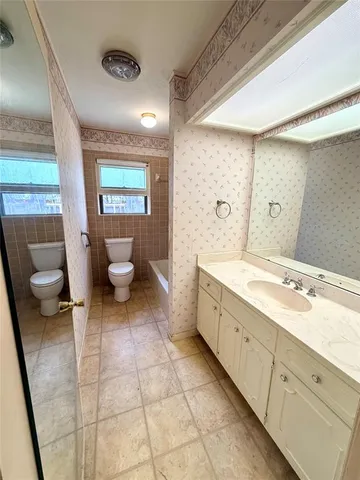 a spacious bathroom with a double vanity sink a mirror and a toilet