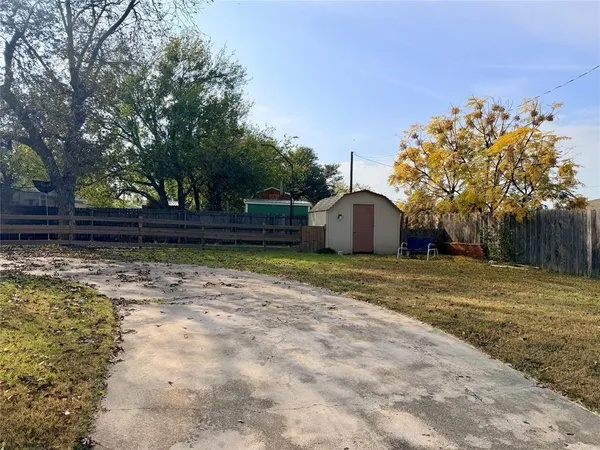 a view of a backyard with large trees and wooden fence