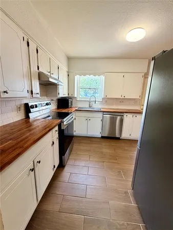 a large kitchen with kitchen island granite countertop a sink a counter top space and cabinets