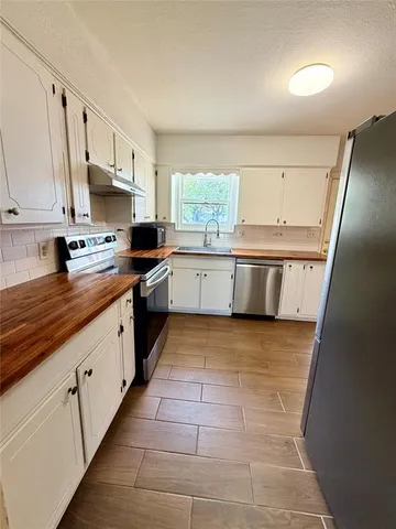 a large kitchen with kitchen island granite countertop a sink a counter top space and cabinets