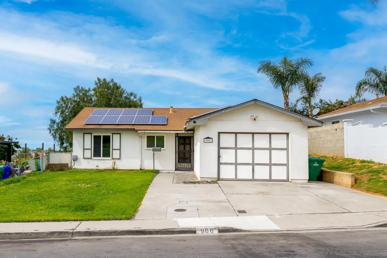 a view of a white house with a large windows and a yard with plants