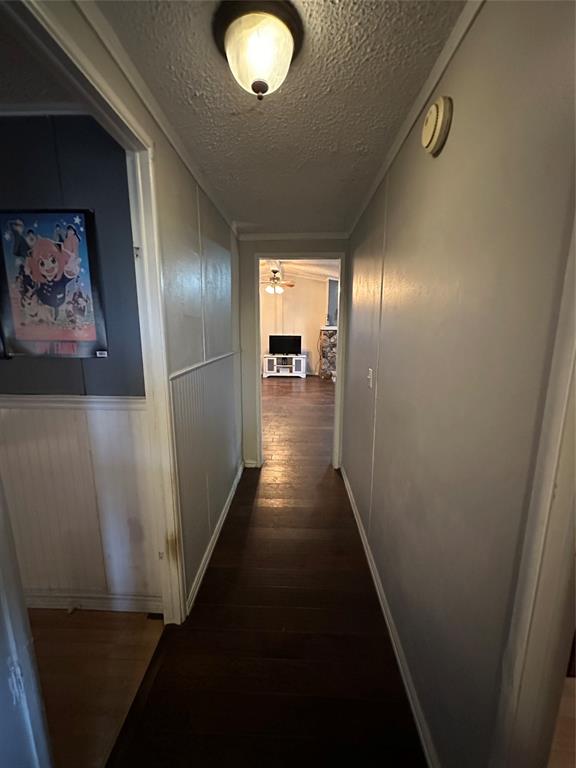 1048 Red Bird Seven Points, TX 75143 - Photo 24 of 30 Hall featuring a textured ceiling, dark wood-type flooring, and a decorative wall