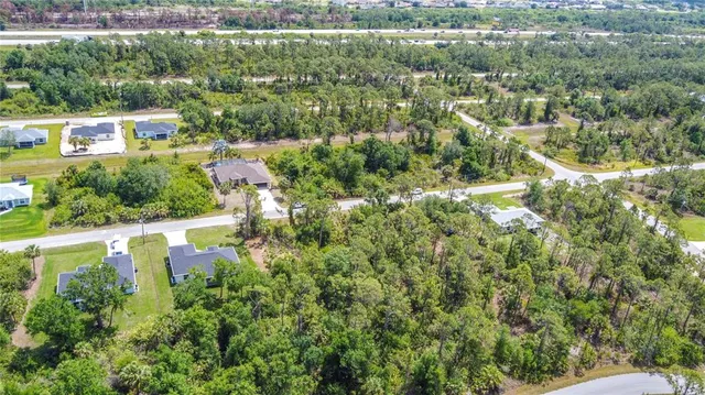 an aerial view of a residential houses with outdoor space and trees
