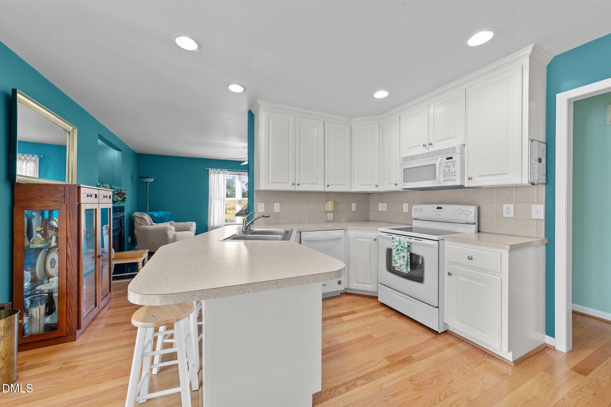 1208 Peach Orchard Road Four Oaks, NC 27524 - Photo 24 of 63 a kitchen with stainless steel appliances kitchen island granite countertop a stove a sink a refrigerator and white cabinets with wooden floor