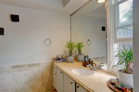 a bathroom with a granite countertop sink a mirror and a potted plant