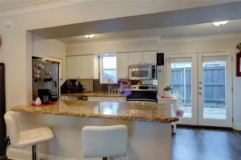 a kitchen with kitchen island granite countertop a stove top oven a sink dishwasher a dining table and chairs with wooden floor