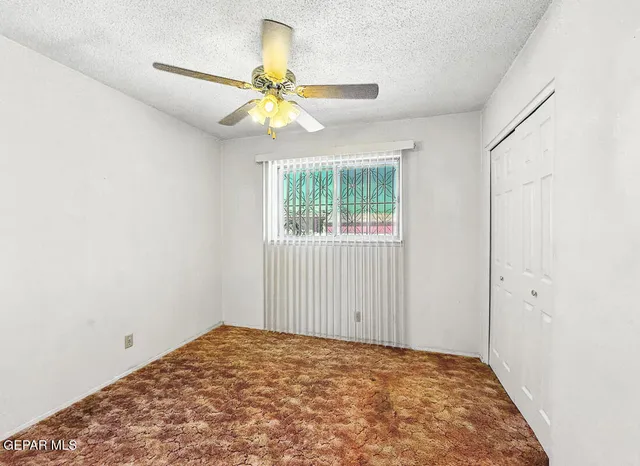 an empty room with windows and fan