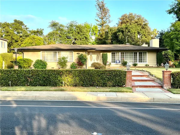 a front view of a house with a yard and potted plants