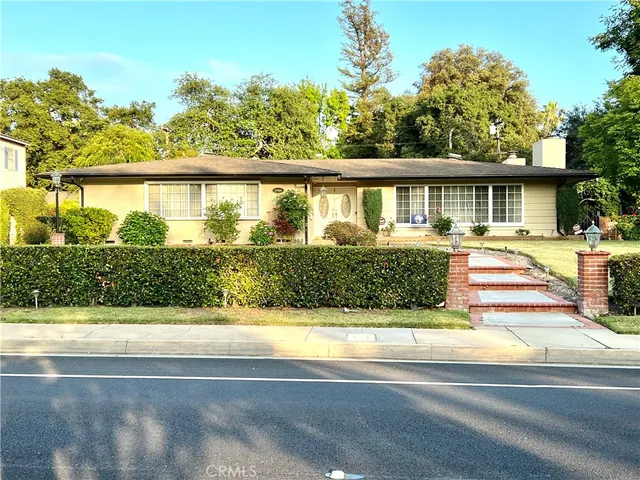 a front view of a house with a yard and potted plants