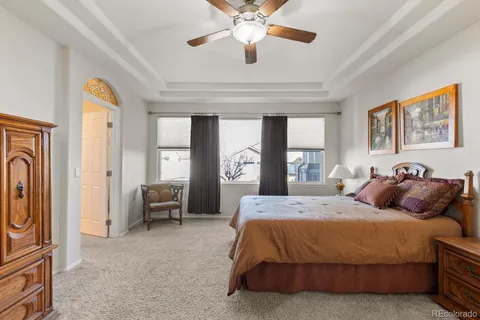 a spacious bedroom with a bed a chandelier and dresser