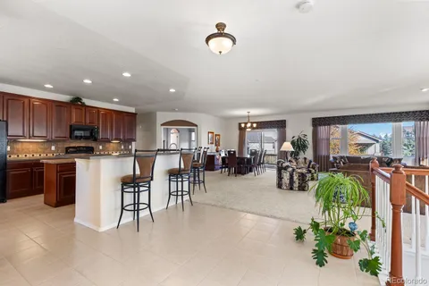 a kitchen with stainless steel appliances granite countertop a refrigerator a sink a stove and a dining table with wooden floor