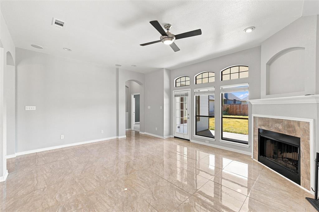 10409 Condor Loop Waco, TX 76708 - Photo 15 of 26 Polished tile flooring, a built-in fireplace with a stone surround, a ceiling fan, recessed lighting, and large windows with arched transoms