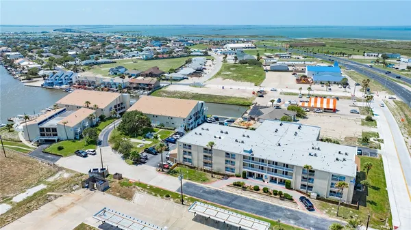 an aerial view of a city with lots of residential buildings and ocean view in back