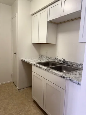a kitchen with granite countertop white cabinets and a sink