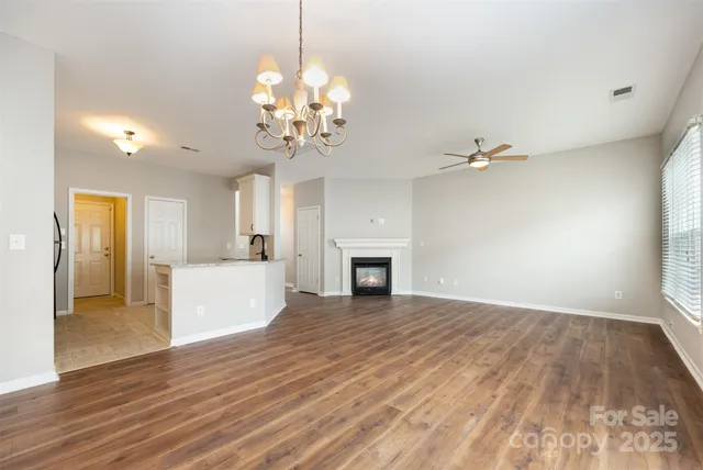 a view of a livingroom with a fireplace wooden floor and chandelier