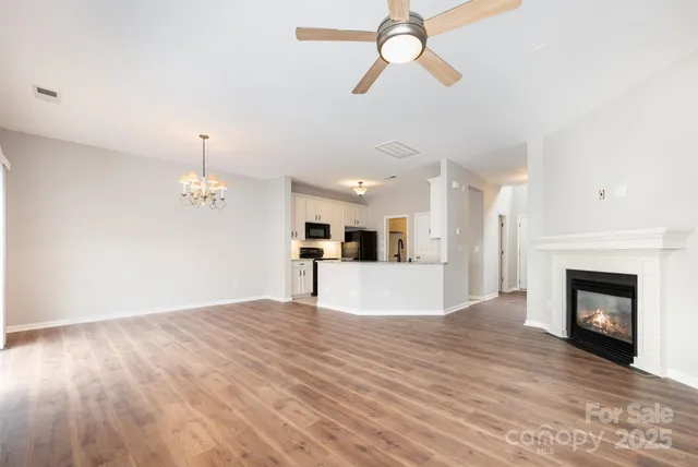 a view of a room with a fireplace a ceiling fan and kitchen view