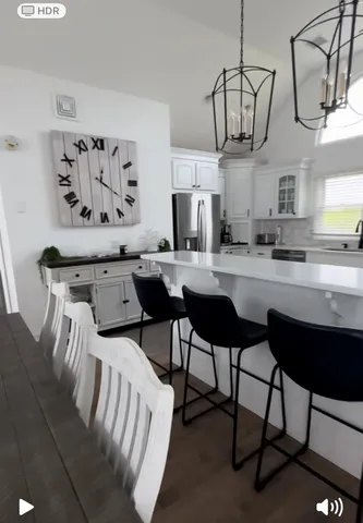 a kitchen with stainless steel appliances kitchen island a table chairs in it and wooden floors