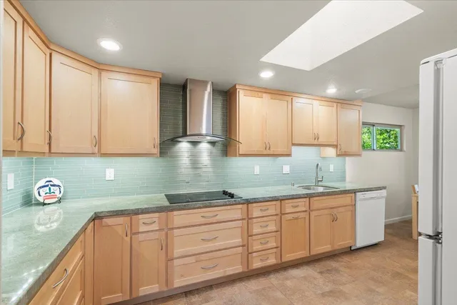 a kitchen with granite countertop a refrigerator a sink a stove and white cabinets
