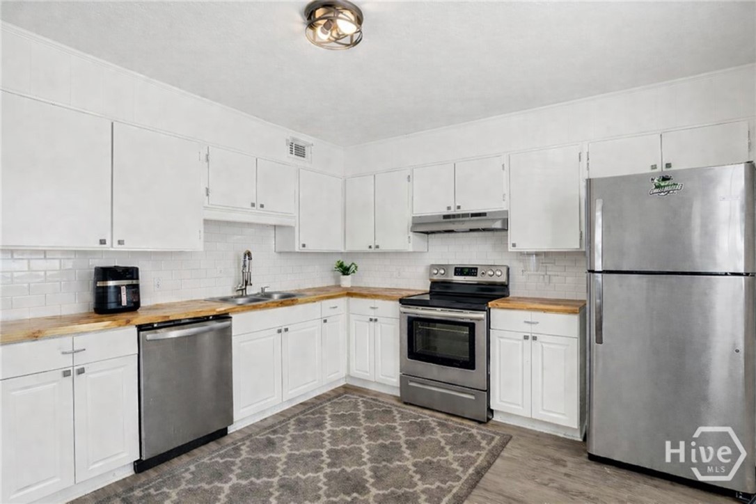 3 Berkley Place Savannah, GA 31405 - Photo 6 of 36 Updated kitchen featuring stainless steel appliances, white cabinetry, and stylish subway tile backsplash.