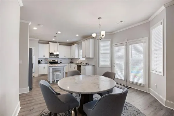 a kitchen with kitchen island a dining table chairs and white cabinets