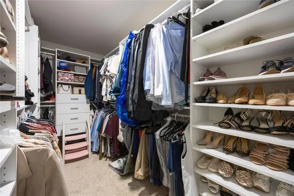 a view of walk in closet with clothes and shoes
