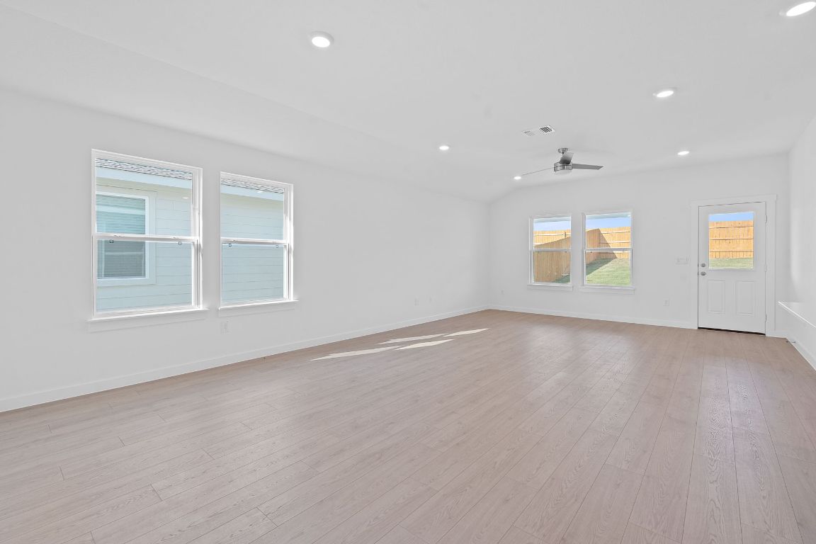 9701 Oxbow Strap Drive Austin, TX 78724 - Photo 11 of 34 Empty room with recessed lighting, light wood-type flooring, a ceiling fan, and vaulted ceiling