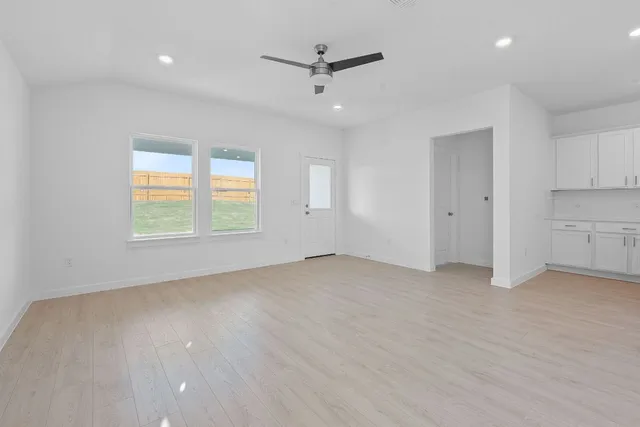 an empty room with windows and ceiling fan