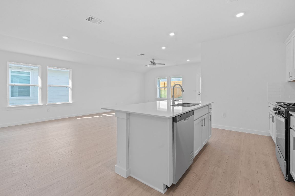 9701 Oxbow Strap Drive Austin, TX 78724 - Photo 34 of 34 Kitchen with white cabinetry, light wood-style flooring, a kitchen island with sink, recessed lighting, and open floor plan