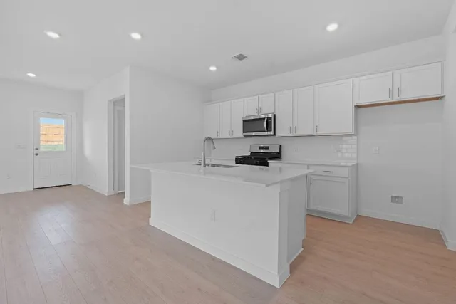 a kitchen with white cabinets and stainless steel appliances